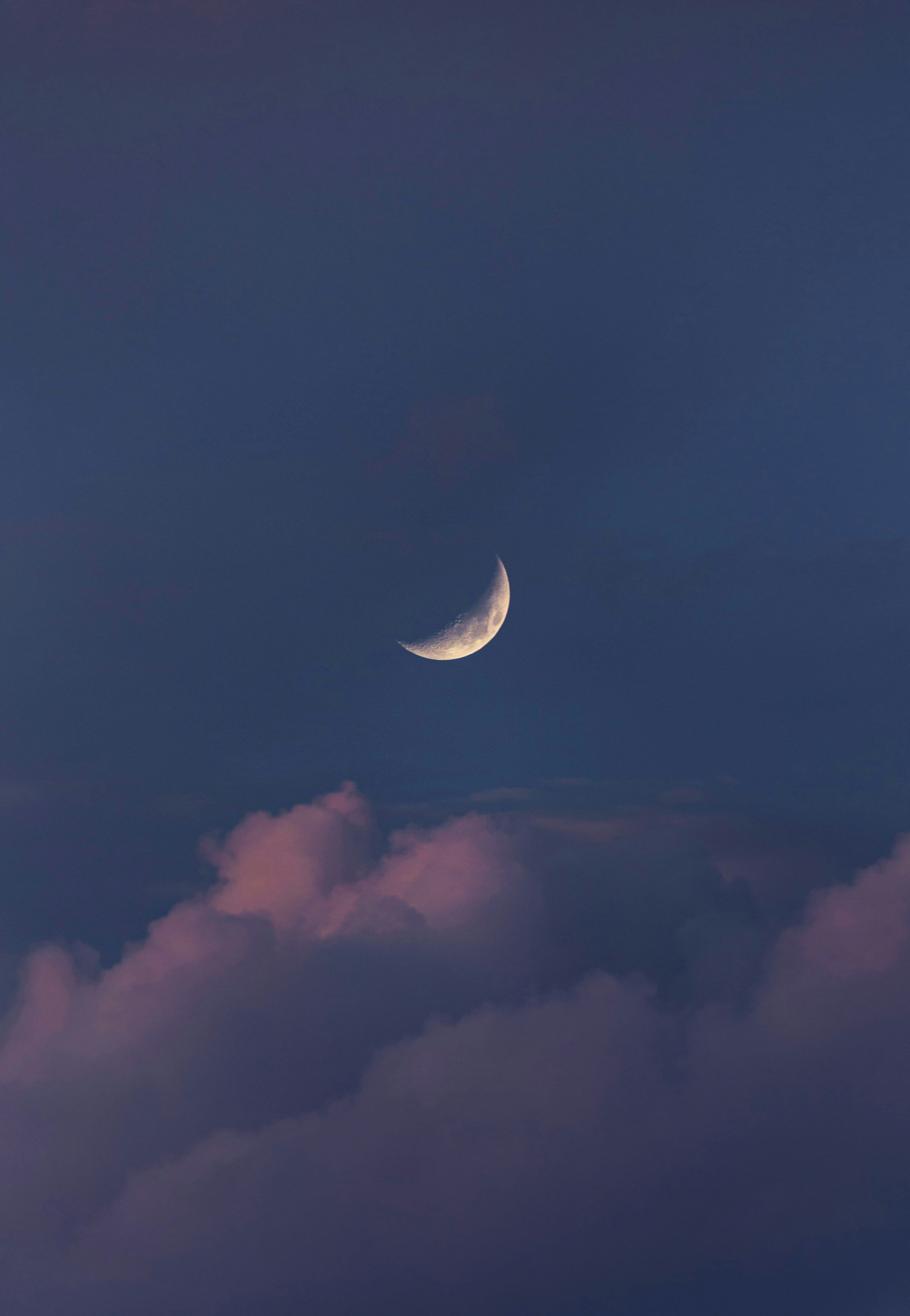 Crescent moon peeking through clouds in a twilight sky,  evoking intuitive guidance and spiritual self-discovery on the journey inward
