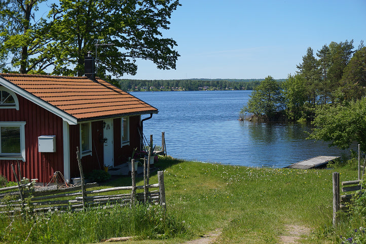 Red cabin by a lake with greenery and clear blue sky,  for 'Create Your Own Mantra Board' to inspire self discovery