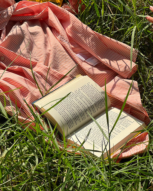 Workbook in the grass on a striped shirt, representing accessible wellness tools for daily spiritual practices and reflection